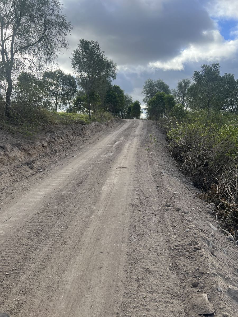 A gravel access track running uphill through scrub on a rural block, the route a truck would need to take