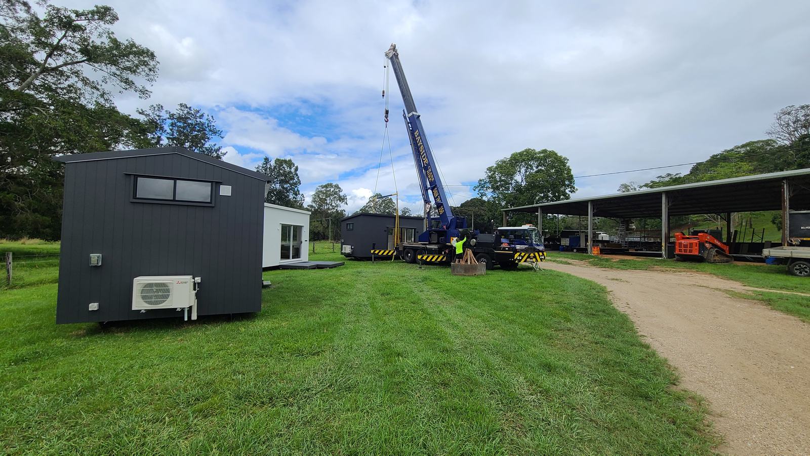 Crane day: a module in the air above a paddock