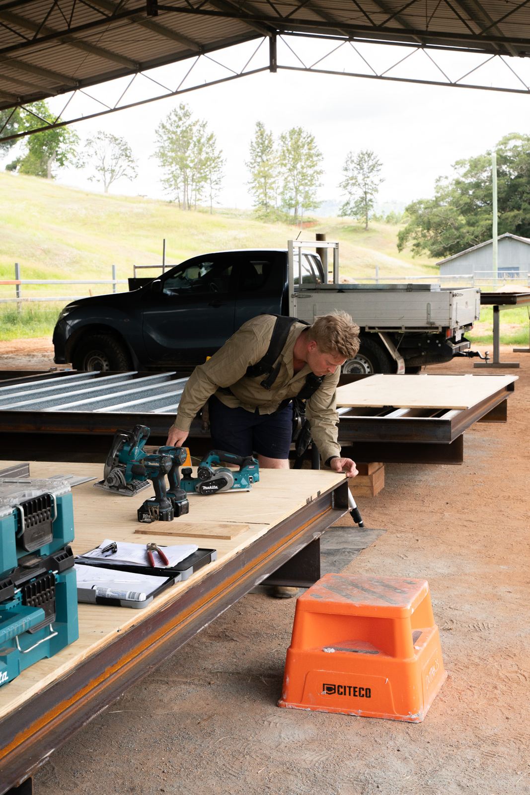 A builder fixing sheeting to a frame on site