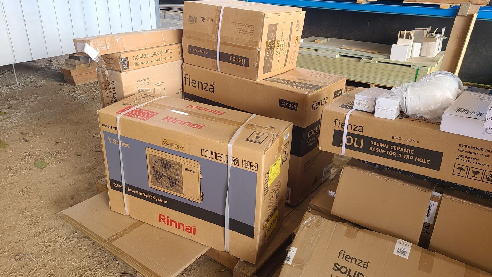 Boxed fixtures for a modular home waiting in the factory: a split system air conditioner, a basin and tapware