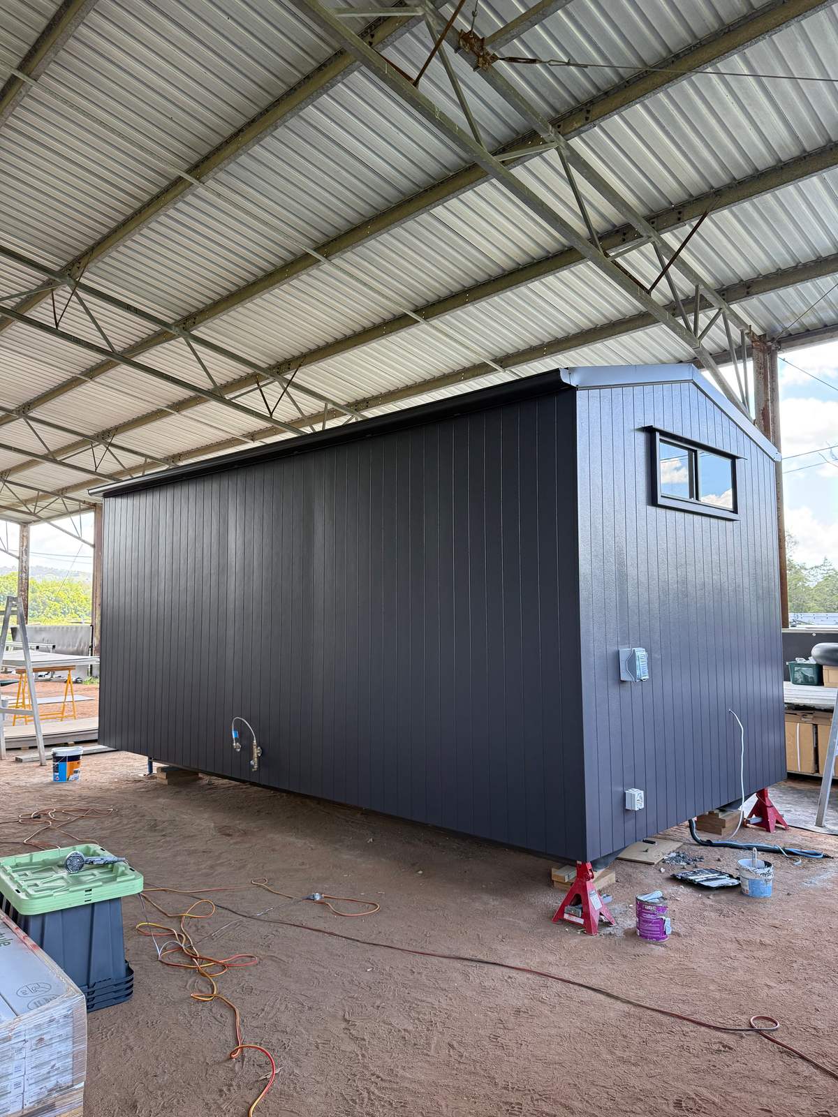 A finished dark-clad module on stands in the shed, ready to leave the factory