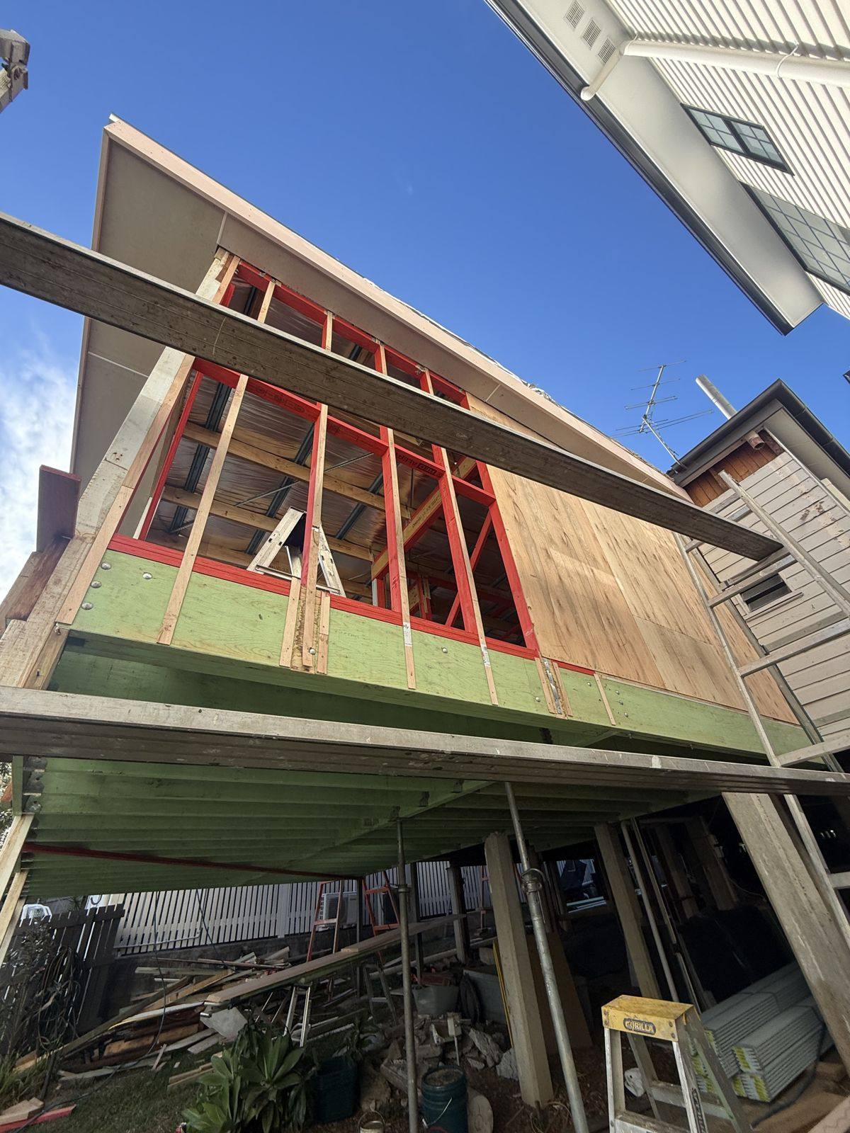 The new extension from below, red frames and window openings, plywood bracing on and the roof overhead