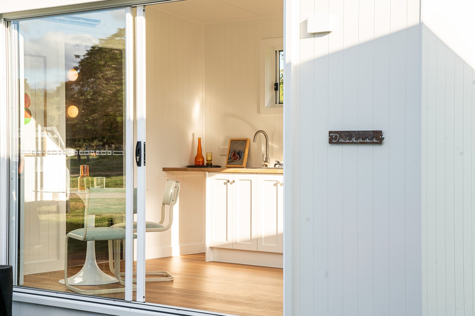 A white second home with its glass doors open onto the deck