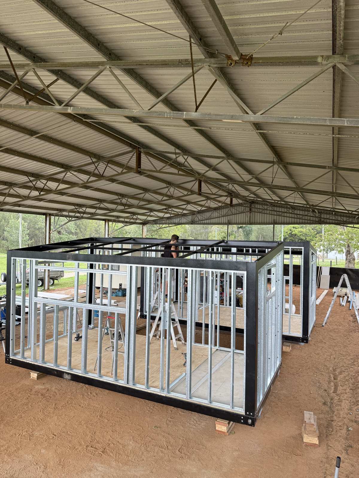 Black steel module chassis and galvanised wall frames standing under a big open shed